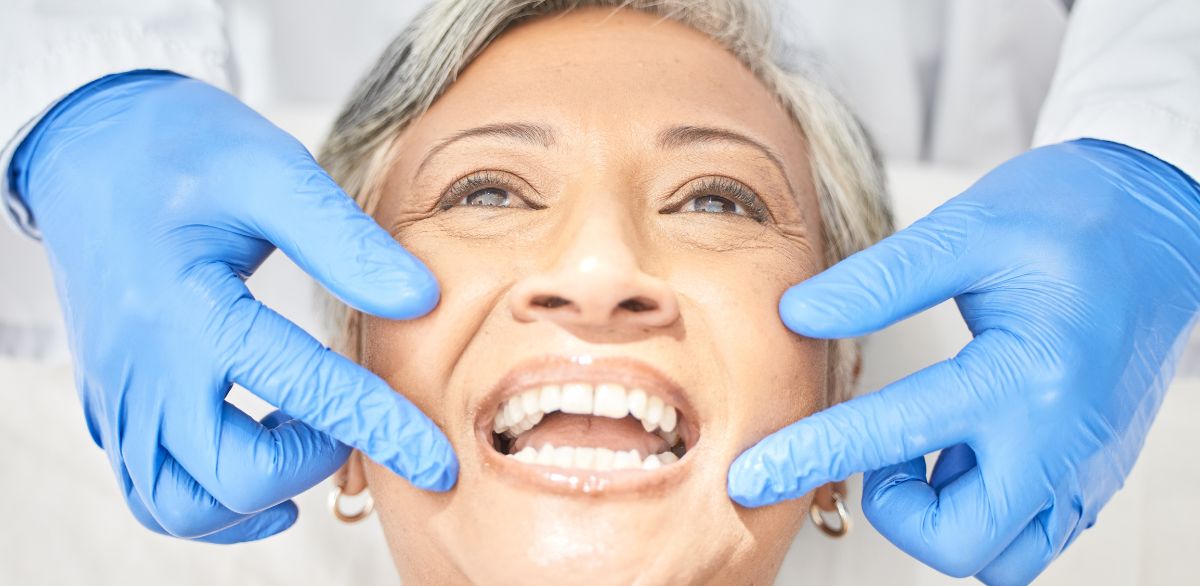 Smiling patient having gums examined by a dentist