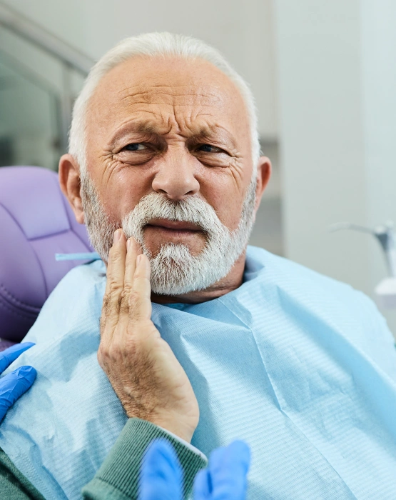 Elderly man holding his jaw during a dental treatment visit